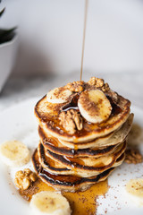 Maple syrup pouring onto a delicious homemade banana pancake stack