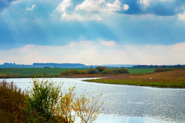 Landscape with river and sunlight penetrating the clouds
