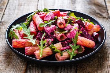 Pasta with beets and feta cheese on wooden table
