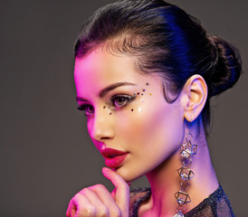 Portrait of beautiful young woman with bright makeup. Shiny sequins on face. Beautiful brunette...
