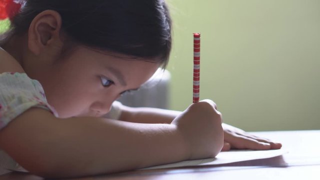 Asian child online study at home or kid girl learning and training for doing homework or coloring and drawing paint with write by pencil on paper notebook with at nursery preschool and kindergarten 4K