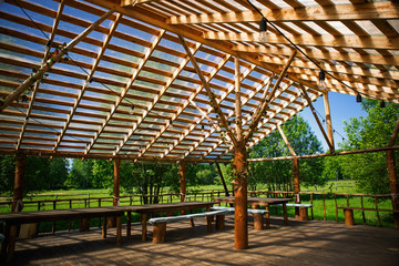 Wooden gazebo in nature in the Park for events. Sunlight through a grid of wooden beams-a game of chiaroscuro. Place for text and background