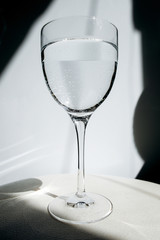 Glass of water on a white background. A glass reflects glare. Transparent glass with wine.