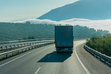 Truck driving on the highway in front of a foggy landscape