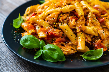 Chicken ragout with penne on wooden table