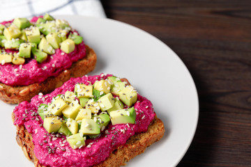Variation of healthy rye toasts with avocado and beetroot on a plate. Delicious snacks, avocado sandwiches. Food composition, tasty vegan food. Close up