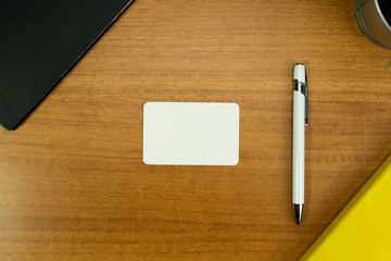 Stationery set with various objects around a white business card with round corners and white pen for mockup purposes