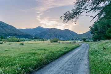 Rural road in a green valley with mountains in the background