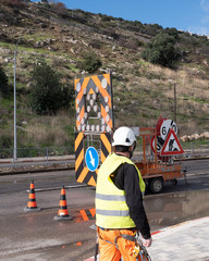 City road servicing after heavy rains. Passage is blocked by red road cones. A worker in a...