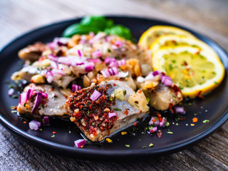 Marinated herrings with lemon and onion on wooden table
