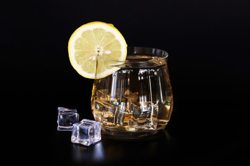 transparent glass with lemon tea, ice and lemon slice isolated on black background