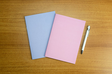 Stationery set with two colored empty notebooks and a white empty pen for mockup purposes
