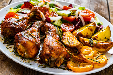 Barbecue chicken drumsticks with vegetables on wooden table