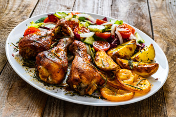 Barbecue chicken drumsticks with vegetables on wooden table
