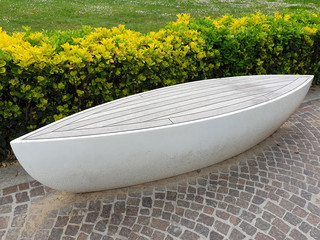 White bench unusual shape in the form of a boat in the park. The modern design of the bench.
