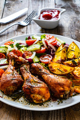 Barbecue chicken drumsticks with vegetables on wooden table