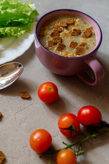 Soup with rye crackers, lettuce and fresh cherry tomatoes on a gray background
