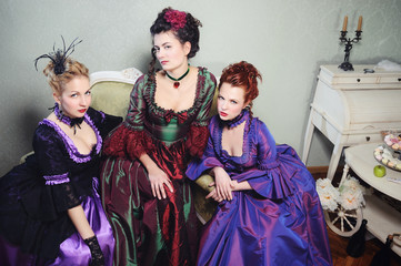 Three beautiful ladies in lavish dresses in a historical setting