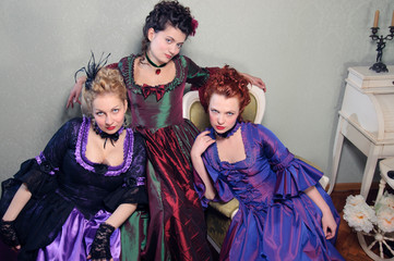 Three beautiful ladies in lavish dresses in a historical setting