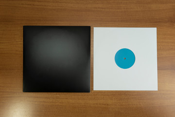 Empty Black Vinyl disk case and square paper case in a wood background for mockup purposes