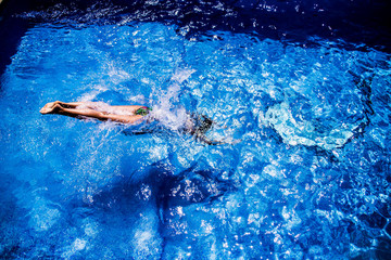 Fototapeta na wymiar Woman diving into water in swimming pool during summertime