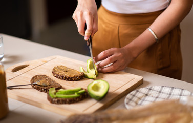 Woman slicing avocado while making avocado peanut butter toast