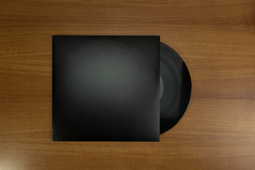 Empty Black Vinyl disk case with vinyl piece in a wood background for mockup purposes