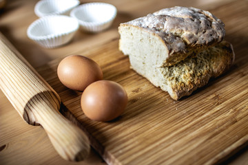 Still life with a piece of bread, eggs, cup papers and a rolling pin on a wooden table