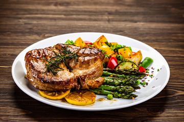 Barbecue beef steak fried potatoes and vegetables on wooden table