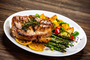 Barbecue beef steak fried potatoes and vegetables on wooden table