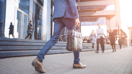 Close Up Leg Shot of a Businessman in a Suit Commuting to the Office on Foot. He's Carrying a...