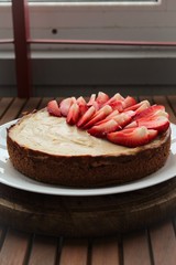 Homemade classic cheesecake, decorated with fresh strawberries.