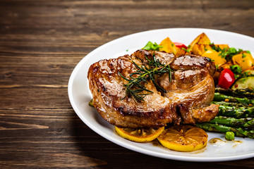 Barbecue beef steak fried potatoes and vegetables on wooden table