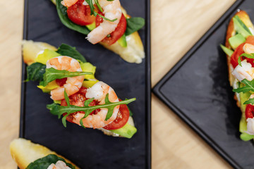 Tasty italian appetizer bruschettes with tomatoes anchovies prosciutto, mozarella, shrimps and seafood