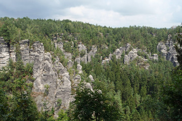 Fototapeta na wymiar Huge black grey colored and fissured sandstone rocks surrounded by forest; Saxon Switzerland, Germany, Europe 