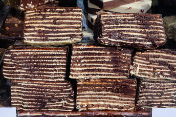 Large portion of Dobos torte or Dobosh, a  traditional Hungarian sponge cake made at home with chocolate, caramelized sugar and biscuits covered,  displayed for sale on a table at a street food market