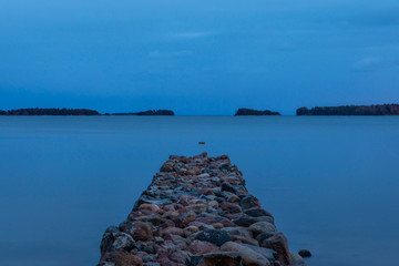 Breakwater reaching to a calm sea on blue hour with no people