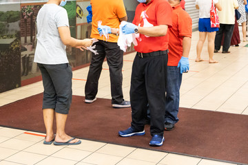 Naklejka premium New normal lifestyle with inspectors requiring shoppers to sanitize hands and put on disposable gloves for protection before entering supermarket