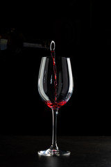 Obraz na płótnie Canvas Rose wine pouring in a glass on black background