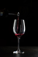 Rose wine pouring in a glass on black background