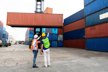 Foreman and staff control loading Containers box from Cargo at industrial container yard. import...