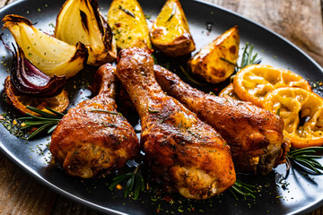 Barbecue chicken drumsticks with vegetables on wooden table