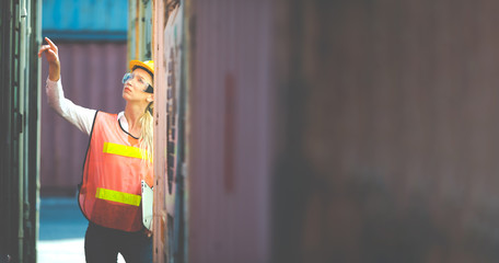 Portrait of Women worker control loading Containers box from Cargo at container yard. Import and Export concept. Marine, carrier and logistic insurance