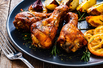 Barbecue chicken drumsticks with vegetables on wooden table