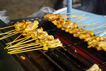 Thai street food BBQ,Pork satay grilling on stove or Thai style roasted pork at the market