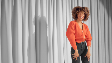 Mixed race black woman with curly hair and natural warm make-up for dark skin Dancing and laughing