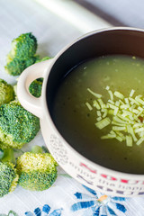 Sopa de verduras decorada con brócoli, puerros y pasta de estrellas con fondo de mantel
