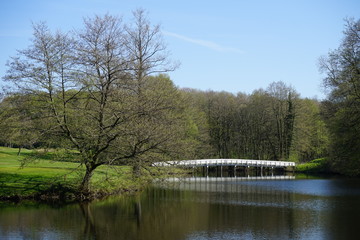 Weiße Brücke führt über einen See, Teich in einer Parkanlage, Frühling