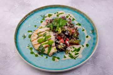 Dorado fillet, salad mix, grapefruit, cream sauce, Tobiko caviar. European cuisine. The work of a professional chef. Dish from a restaurant or cafe menu. Side view