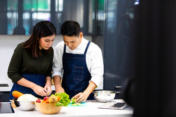 Beautiful young Asian couple preparing a healthy meal together at home. Romantic couple cooking together on kitchen.